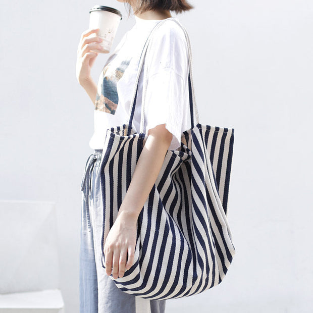 Woman carrying a large striped canvas shoulder tote bag for casual shopping