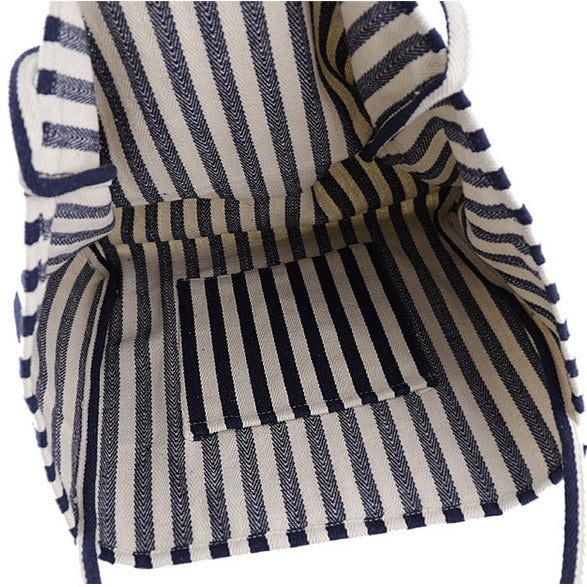 Interior view of a striped canvas bag showing navy and white vertical stripes with a small inner pocket, designed as a high capacity shoulder tote for casual shopping.