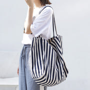 woman carrying large striped canvas shoulder bag tote for casual shopping