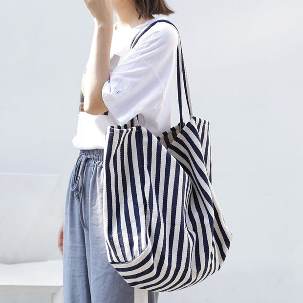 woman carrying large striped canvas shoulder bag tote for casual shopping
