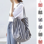 woman carrying large striped canvas bag high capacity shoulder tote casual shopper handbag in navy and white stripes with multiple color options