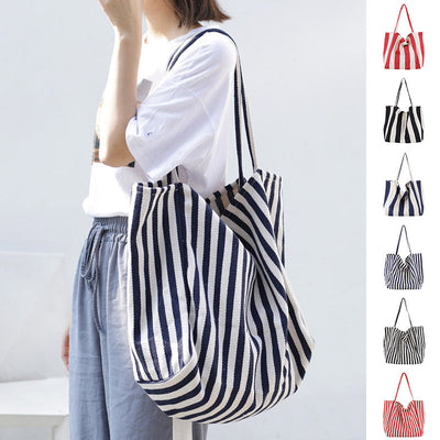 woman carrying large striped canvas bag high capacity shoulder tote casual shopper handbag in navy and white stripes with multiple color options