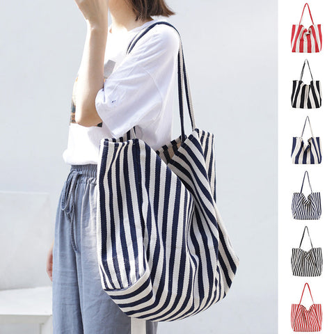 woman carrying large striped canvas bag high capacity shoulder tote casual shopper handbag in navy and white stripes with multiple color options