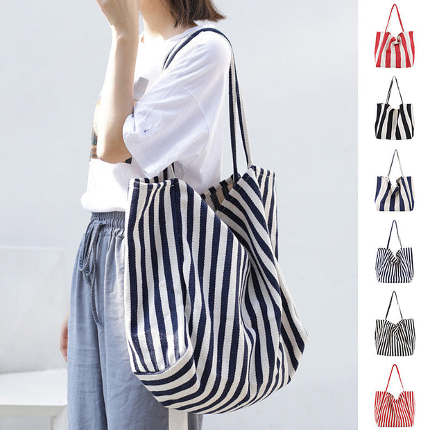 woman carrying large striped canvas bag high capacity shoulder tote casual shopper handbag in navy and white stripes with multiple color options
