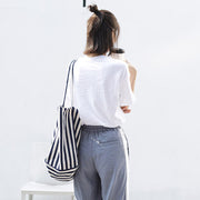 Woman carrying a high capacity striped canvas shoulder bag in black and white stripes, casual fashion tote for shopping