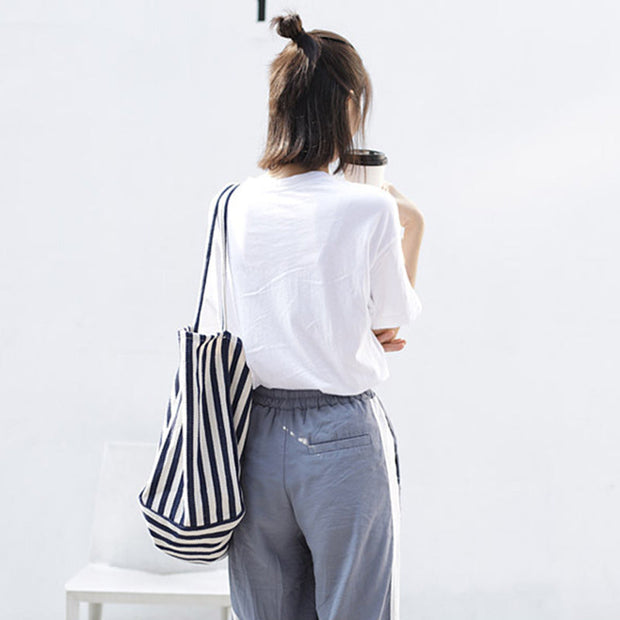 Woman carrying a high capacity striped canvas shoulder bag in black and white stripes, casual fashion tote for shopping