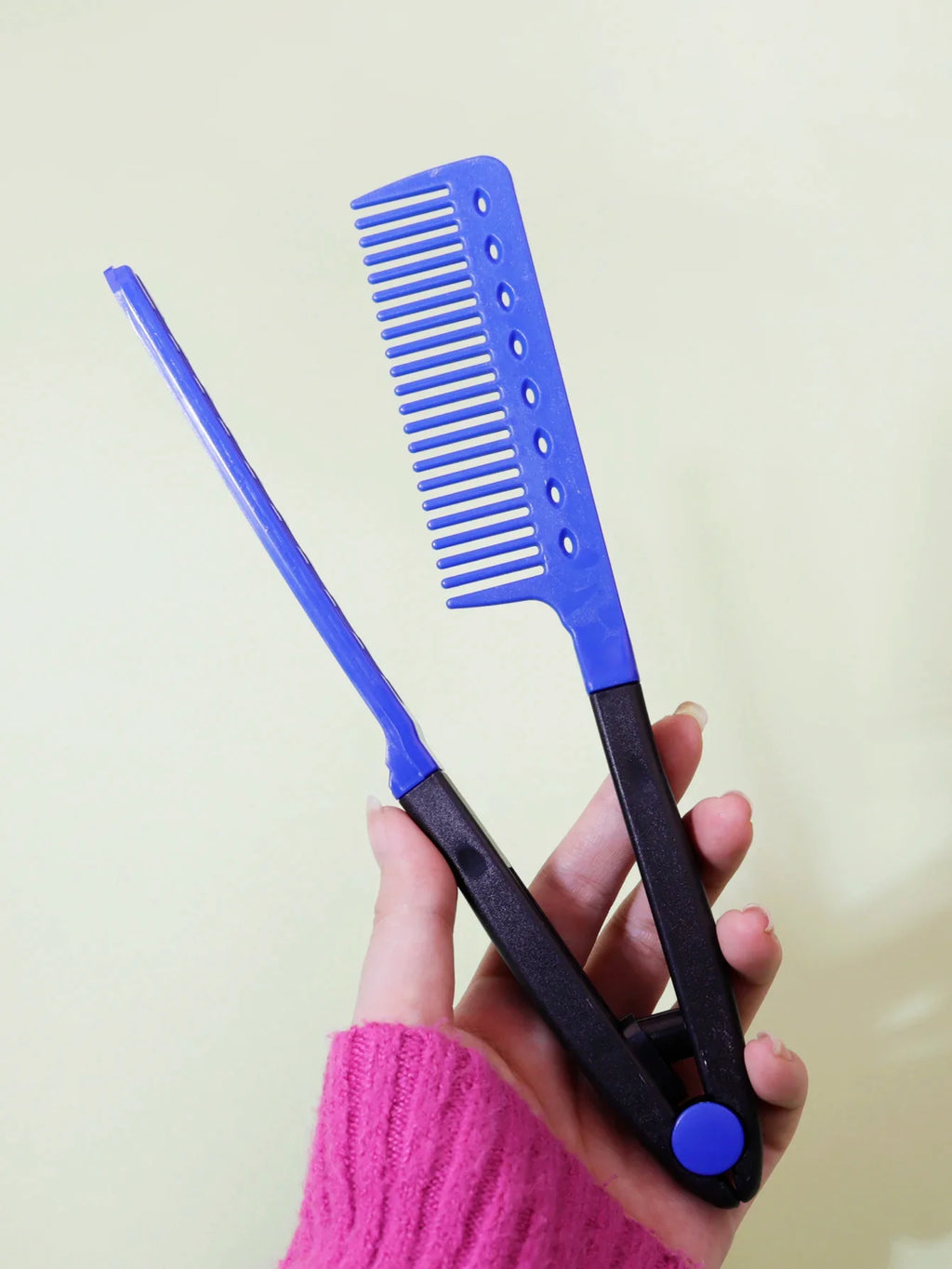 blue and black flat comb straight hair styling tool with V-shaped teeth held in hand