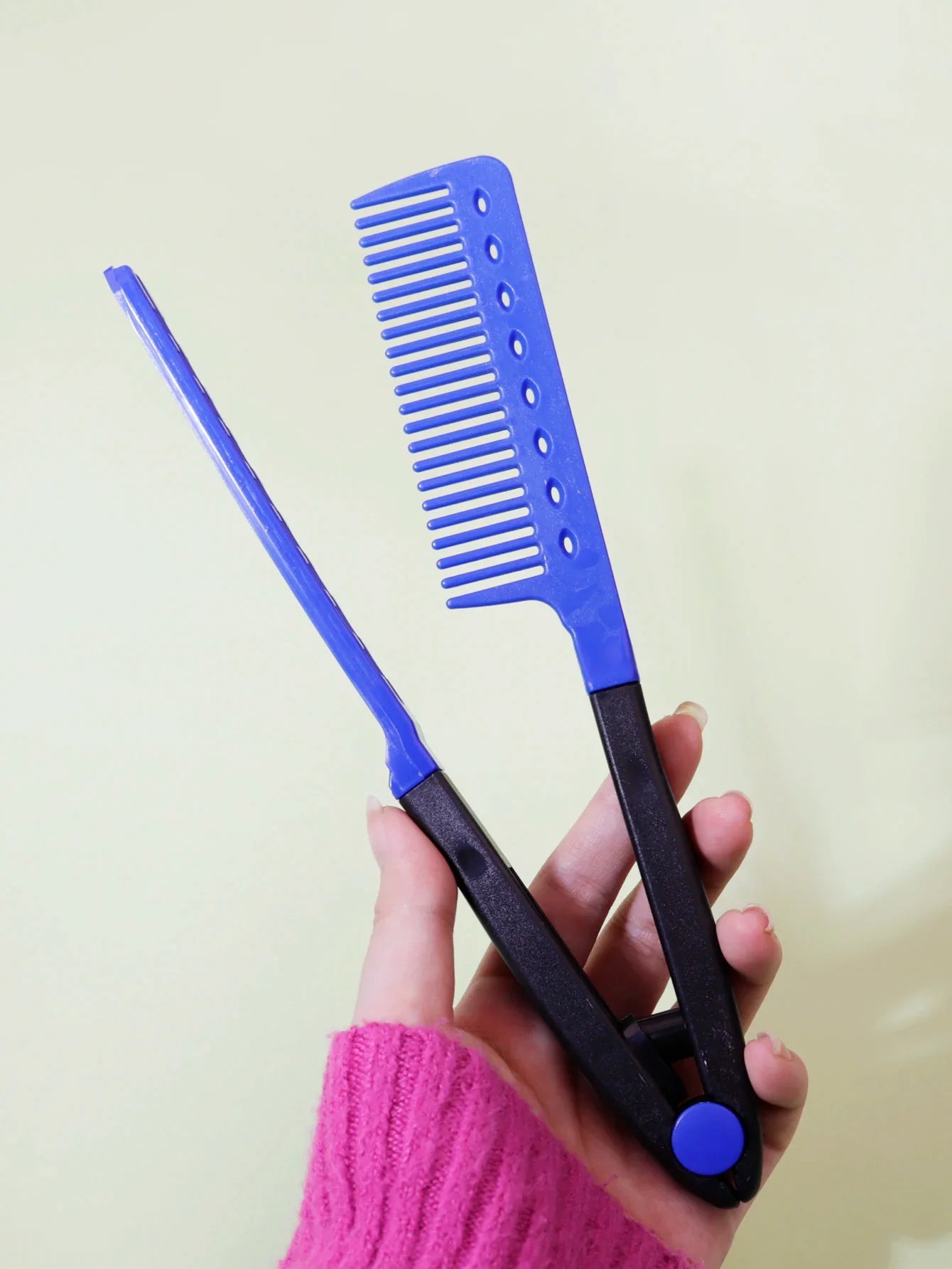 blue and black flat comb straight hair styling tool with V-shaped teeth held in hand
