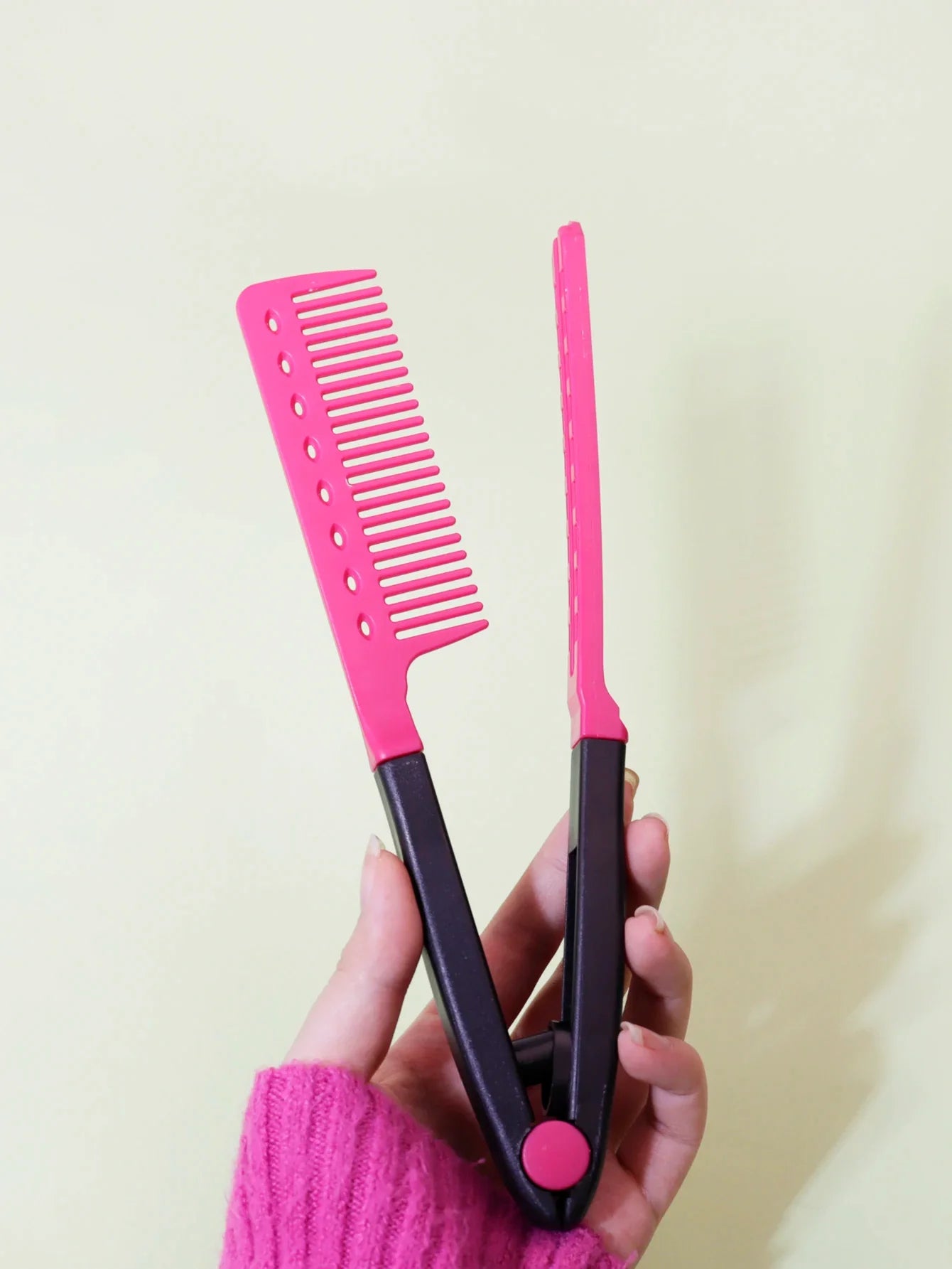 pink and black flat comb straight hair styling brush comb straightener held in hand