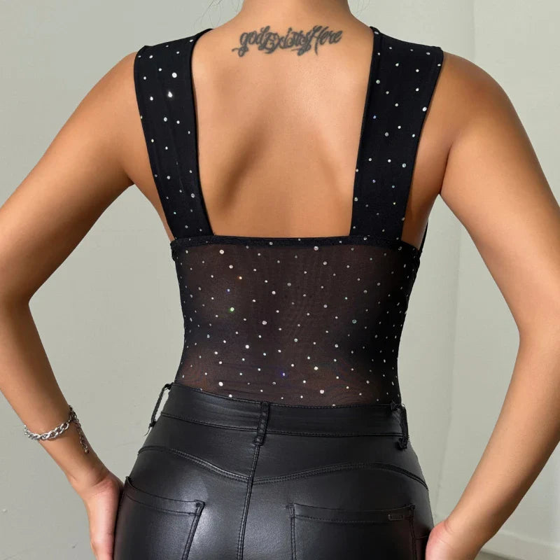 Back view of women's black sequin jumpsuit with sheer fabric and wide shoulder straps, paired with black leather pants.