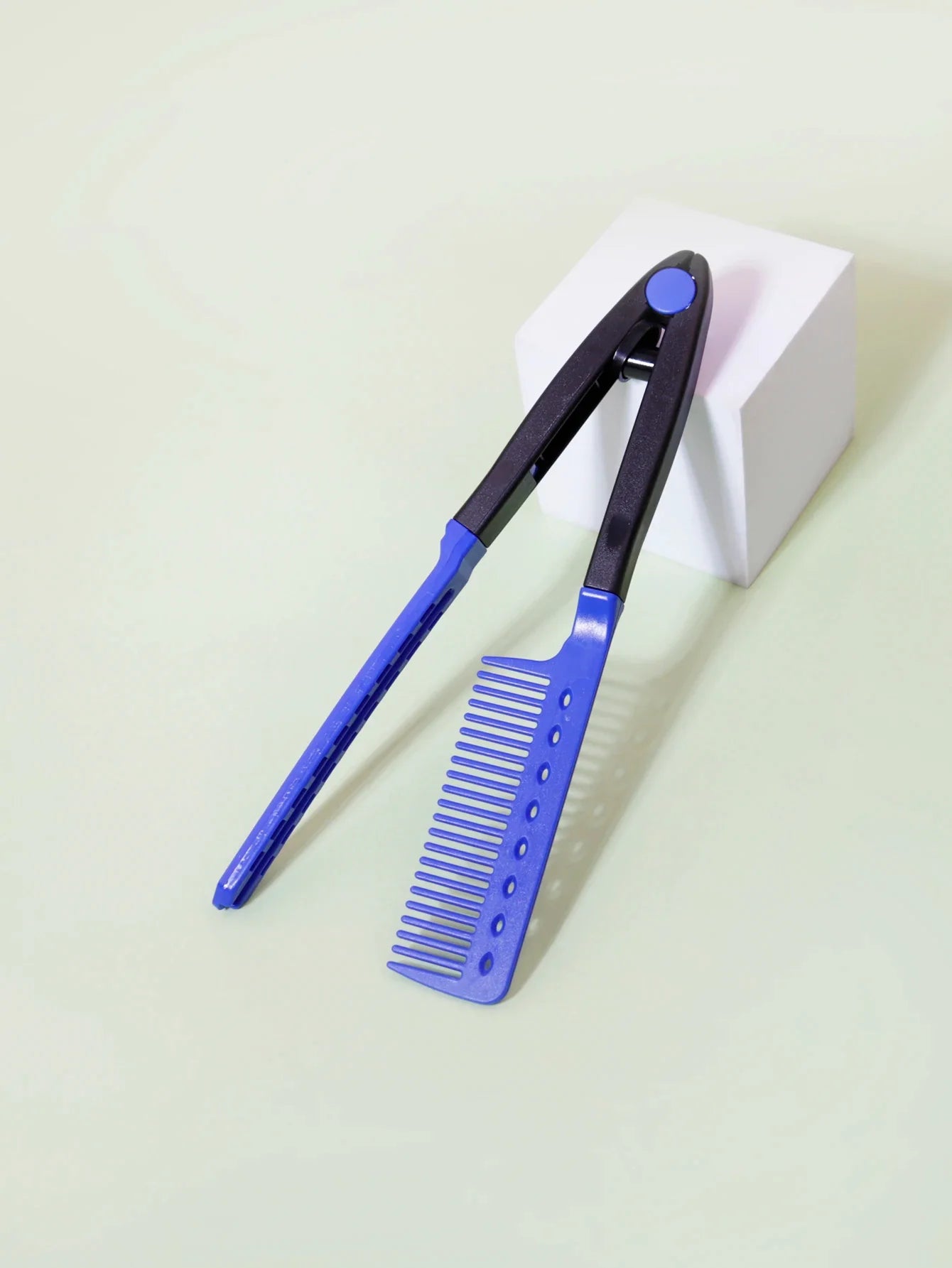 blue and black flat comb straight hair styling tool with V-shaped design on white block background