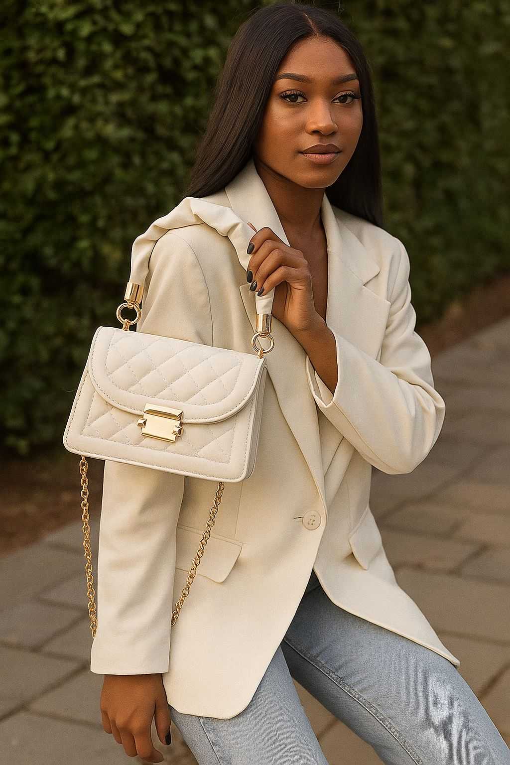 Woman wearing beige blazer carrying white grid pattern tote bag with gold chain strap and buckle flap closure outdoors